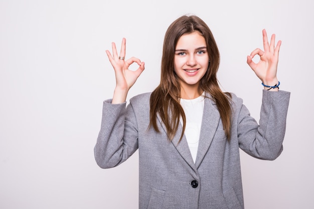 La bella donna che gesturing un lavoro eccellente firma sopra il fondo bianco