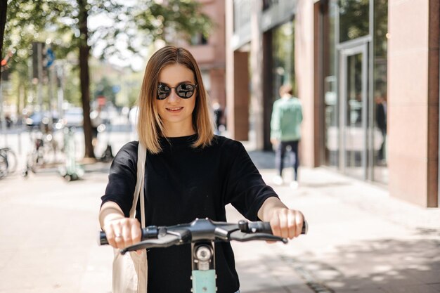 La bella donna con la bici sorride alla macchina fotografica sulla via