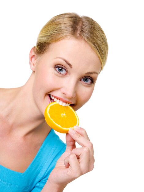 La bella donna felice mangia la fetta della fetta d'arancia fresca - su bianco