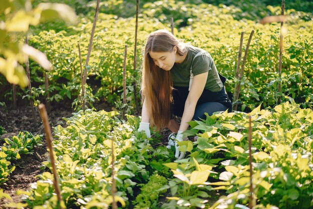 La bella donna lavora in un giardino vicino alla casa