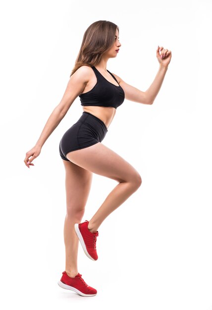 La bella donna sexy castana in abiti sportivi neri fa gli esercizi per il corpo della forte figura