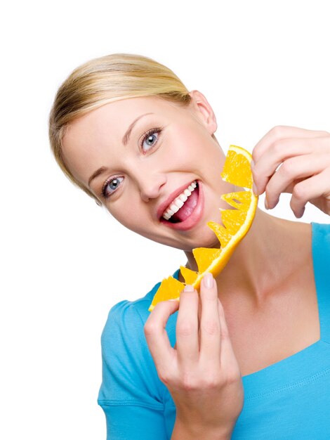 La bella femmina sorridente mangia l'arancia fresca