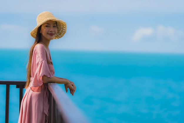 La bella giovane donna asiatica del ritratto che guarda l'oceano della spiaggia del mare per si rilassa nel viaggio di vacanza di festa