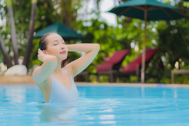 La bella giovane donna asiatica del ritratto gode di relax sorriso svago intorno alla piscina all'aperto in hotel