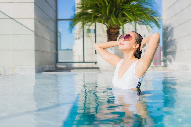 La bella giovane donna asiatica del ritratto rilassa lo svago intorno alla piscina