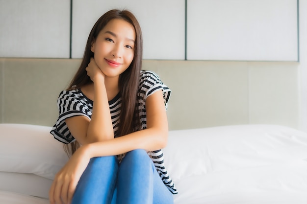 La bella giovane donna asiatica del ritratto si rilassa il sorriso felice in camera da letto