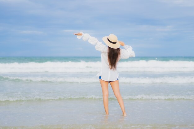 La bella giovane donna asiatica del ritratto si rilassa il sorriso intorno all'oceano del mare della spiaggia nel viaggio di viaggio di vacanza di festa