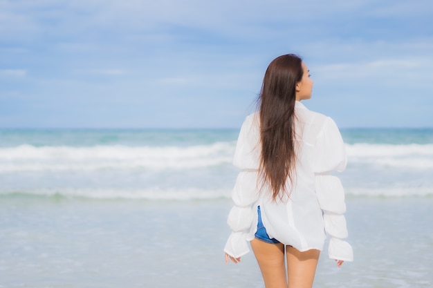 La bella giovane donna asiatica del ritratto si rilassa il sorriso intorno all'oceano del mare della spiaggia nel viaggio di viaggio di vacanza di festa