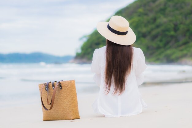 La bella giovane donna asiatica del ritratto si rilassa il sorriso intorno all'oceano del mare della spiaggia nel viaggio di viaggio di vacanza di festa