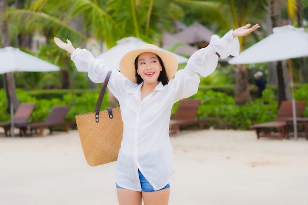 La bella giovane donna asiatica del ritratto si rilassa il sorriso intorno all'oceano del mare della spiaggia nel viaggio di viaggio di vacanza di festa