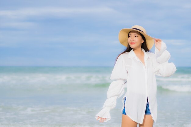 La bella giovane donna asiatica del ritratto si rilassa il sorriso intorno all'oceano del mare della spiaggia nel viaggio di viaggio di vacanza di festa