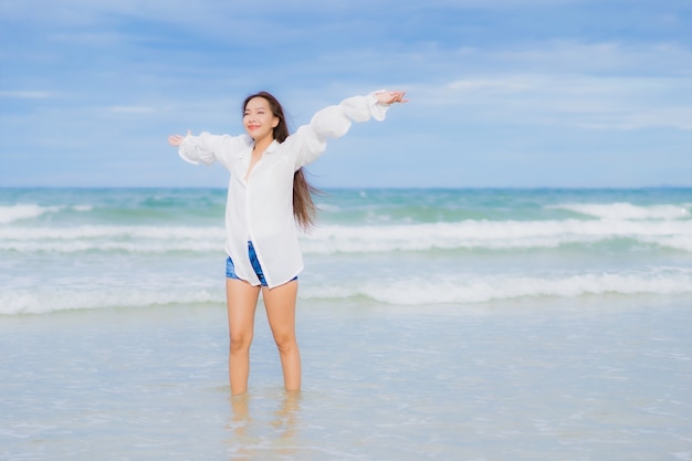 La bella giovane donna asiatica del ritratto si rilassa il sorriso intorno all'oceano del mare della spiaggia nel viaggio di viaggio di vacanza di festa