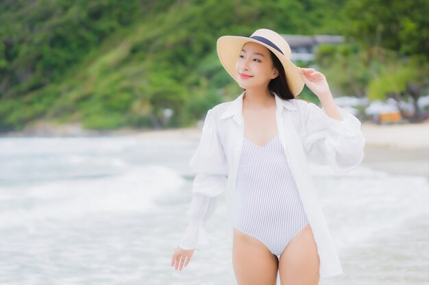 La bella giovane donna asiatica del ritratto si rilassa il sorriso intorno all'oceano del mare della spiaggia nel viaggio di viaggio di vacanza di festa