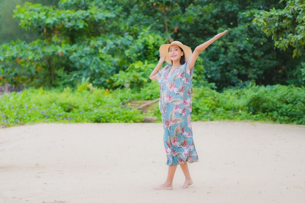 La bella giovane donna asiatica del ritratto si rilassa il sorriso intorno all'oceano del mare della spiaggia nella vacanza di festa