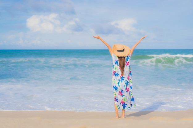 La bella giovane donna asiatica del ritratto si rilassa il sorriso intorno all'oceano del mare della spiaggia nella vacanza di festa