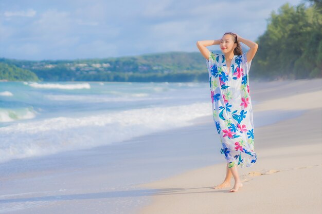 La bella giovane donna asiatica del ritratto si rilassa il sorriso intorno all'oceano del mare della spiaggia nella vacanza di festa