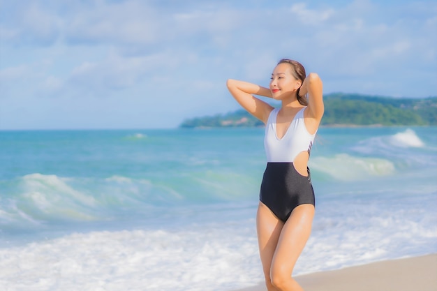 La bella giovane donna asiatica del ritratto si rilassa il sorriso intorno all'oceano del mare della spiaggia nella vacanza di festa