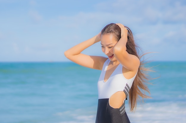 La bella giovane donna asiatica del ritratto si rilassa il sorriso intorno all'oceano del mare della spiaggia nella vacanza di festa