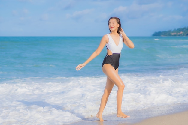 La bella giovane donna asiatica del ritratto si rilassa il sorriso intorno all'oceano del mare della spiaggia nella vacanza di festa