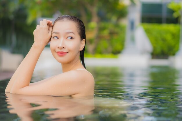 La bella giovane donna asiatica del ritratto si rilassa il sorriso intorno alla piscina all'aperto nella località di soggiorno dell'hotel sul viaggio di vacanza