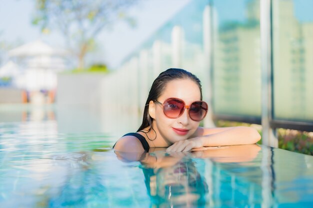 La bella giovane donna asiatica del ritratto si rilassa il sorriso intorno alla piscina all'aperto nella località di soggiorno dell'hotel