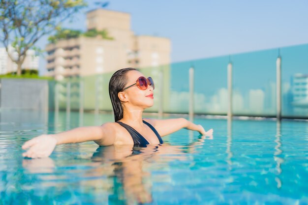 La bella giovane donna asiatica del ritratto si rilassa il sorriso intorno alla piscina all'aperto nella località di soggiorno dell'hotel