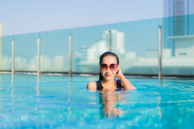 La bella giovane donna asiatica del ritratto si rilassa il sorriso intorno alla piscina all'aperto nella località di soggiorno dell'hotel