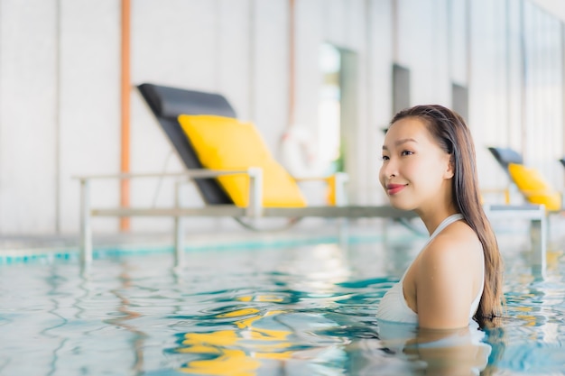 La bella giovane donna asiatica del ritratto si rilassa il sorriso intorno alla piscina nella località di soggiorno dell'hotel sulla vacanza di traval