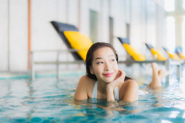 La bella giovane donna asiatica del ritratto si rilassa il sorriso intorno alla piscina nella località di soggiorno dell'hotel sulla vacanza di traval