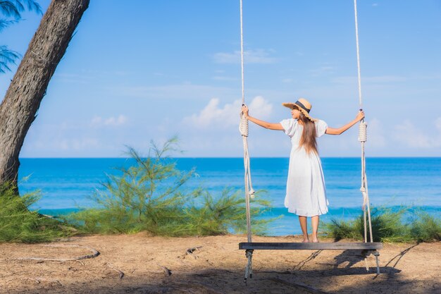 La bella giovane donna asiatica del ritratto si rilassa il sorriso sull'oscillazione intorno all'oceano del mare della spiaggia per il viaggio della natura in vacanza