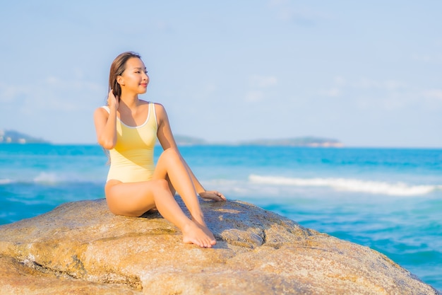 La bella giovane donna asiatica del ritratto si rilassa il tempo libero di sorriso intorno all'oceano del mare della spiaggia sul viaggio di vacanza di viaggio