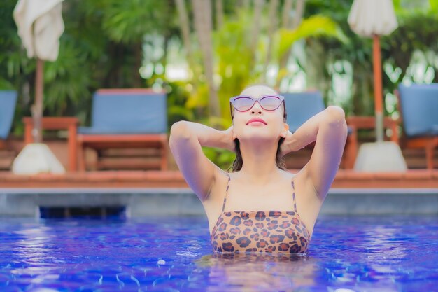 La bella giovane donna asiatica del ritratto si rilassa il tempo libero di sorriso intorno alla piscina all'aperto nei viaggi di viaggio di vacanza di festa