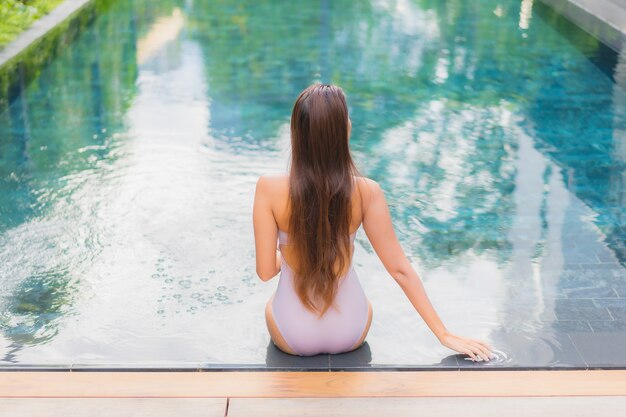 La bella giovane donna asiatica del ritratto si rilassa il tempo libero di sorriso intorno alla piscina all'aperto nella località di soggiorno dell'hotel