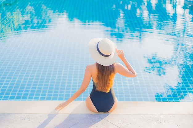 La bella giovane donna asiatica del ritratto si rilassa il tempo libero di sorriso intorno alla piscina all'aperto quasi il mare