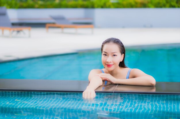 La bella giovane donna asiatica del ritratto si rilassa il tempo libero di sorriso intorno alla piscina all'aperto