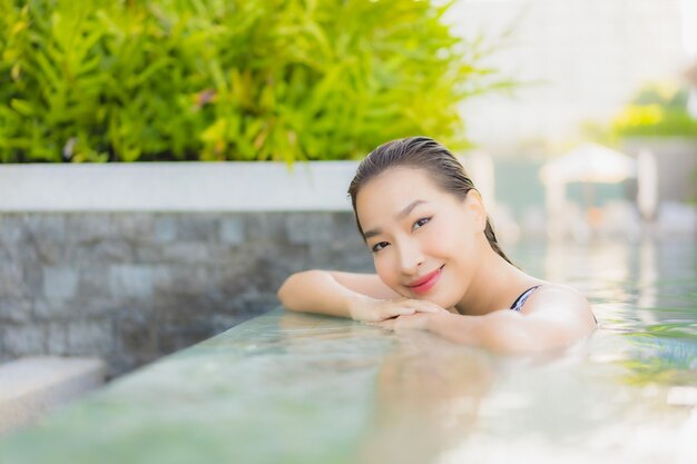 La bella giovane donna asiatica del ritratto si rilassa il tempo libero di sorriso intorno alla piscina all'aperto