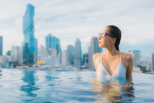 La bella giovane donna asiatica del ritratto si rilassa lo svago felice di sorriso intorno alla piscina all'aperto