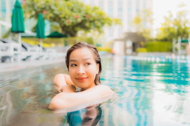 La bella giovane donna asiatica del ritratto si rilassa lo svago felice di sorriso intorno alla piscina all'aperto