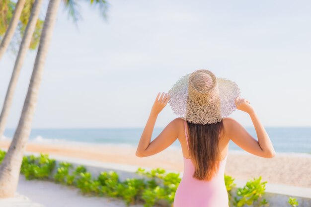 La bella giovane donna asiatica del ritratto si rilassa lo svago intorno alla piscina all'aperto con il mare