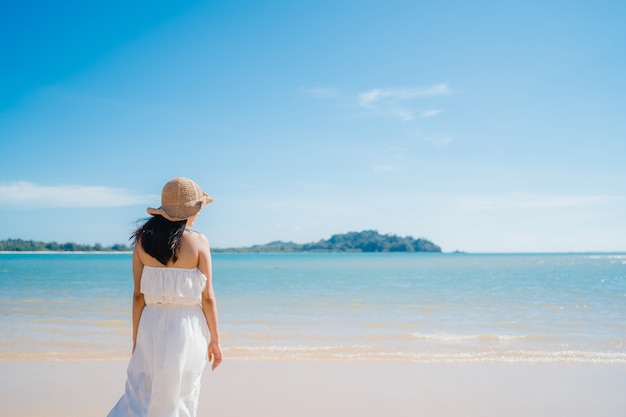 La bella giovane donna asiatica felice si rilassa camminando sulla spiaggia vicino al mare.