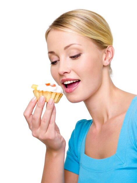 La bella giovane donna mangia la torta dolce con crema bianca