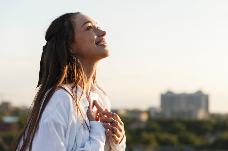 Foto gratuito la bella giovane donna sorride tenere tenero sul tetto nei raggi del sole di sera