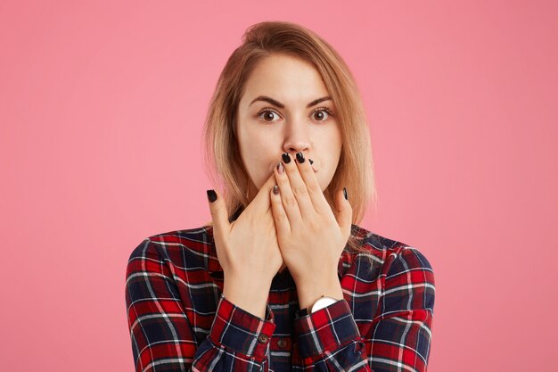 La bella giovane femmina cerca di mantenere il silenzio, non di pettegolezzi e di dire che informazioni riservate si sono coperte la bocca con le mani