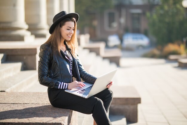 La bella giovane ragazza dell'allievo della donna di affari lavora con il suo computer portatile di marca