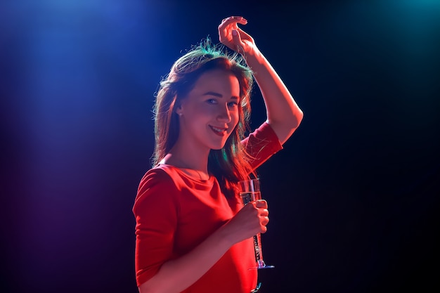 La bella ragazza che balla alla festa bevendo champagne