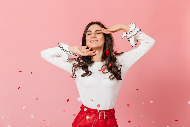 La bella ragazza con le guance increspate sta sorridendo. Donna in abito elegante sa di sfondo rosa.