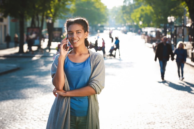 La bella ragazza dalla pelle scura allegra ha parlato sul telefono