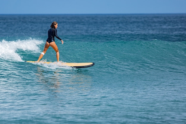 La bella ragazza del surfista cavalca una tavola da surf.