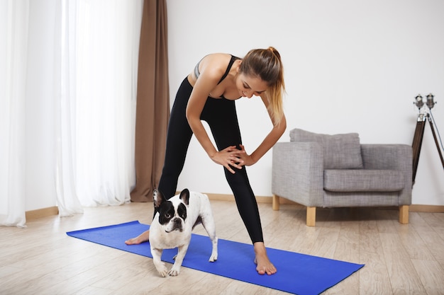 La bella ragazza di forma fisica fa gli esercizi di sport con il cane