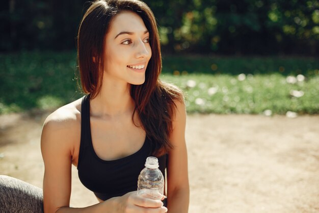 La bella ragazza di sport in un parco dell&#39;estate